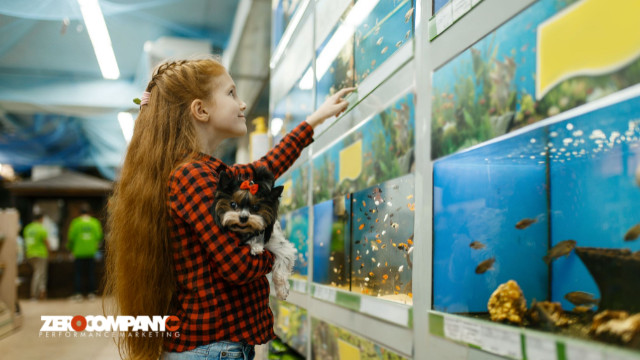 girl looking on fishes in aquarium pet store